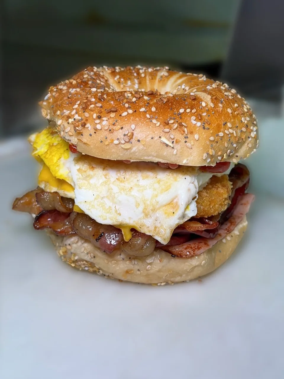 Egg, cheese and breakfast meat stacked on a sesame bagel